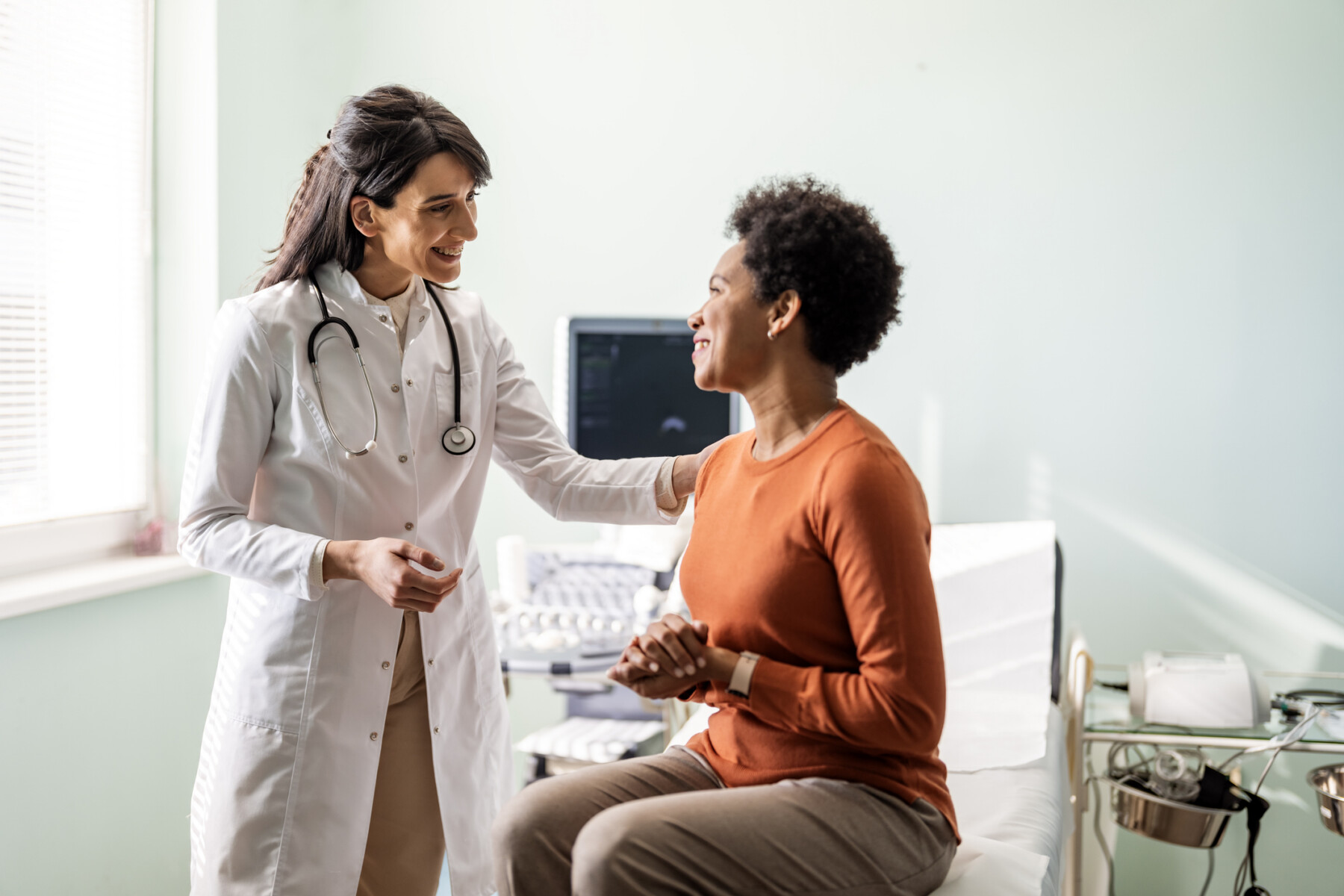 A doctor consults with a patient seated on an examination table.